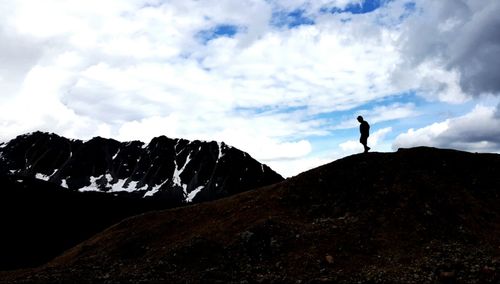 Man standing on mountain against cloudy sky