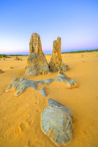 Rock on beach against clear sky