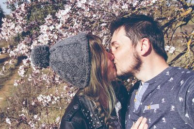 Young couple kissing against trees