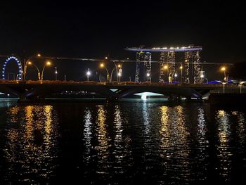 Illuminated bridge over river in city at night