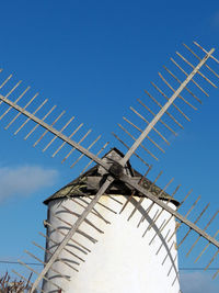Low angle view of windmill against clear blue sky