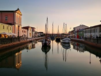 Boats moored at harbor against sky during sunset