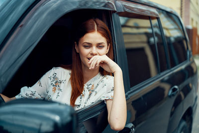 Portrait of young woman sitting in car