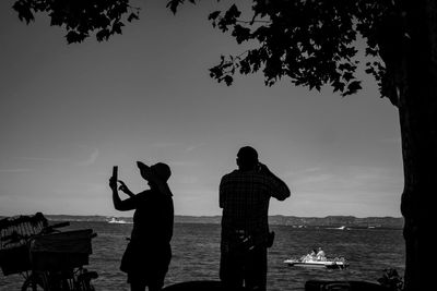 Silhouette people standing on beach against sky