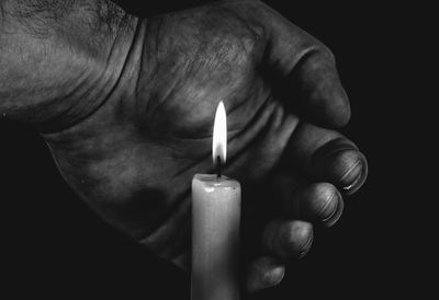 Close-up of hand holding burning candle