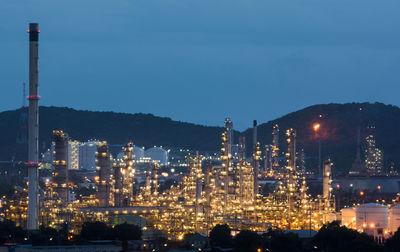 Illuminated factory against sky at night