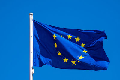 Low angle view of flag against blue sky