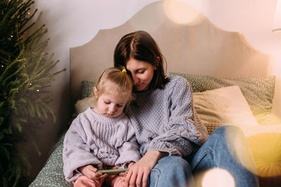 High angle view of young woman sitting on bed at home