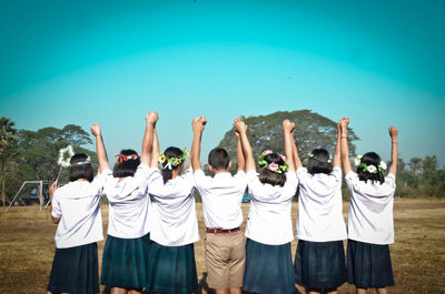 Rear view of men standing against clear blue sky