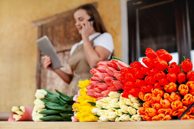 Close-up of bouquets of tulips a female florist with a tablet in her hands is talking on the phone 