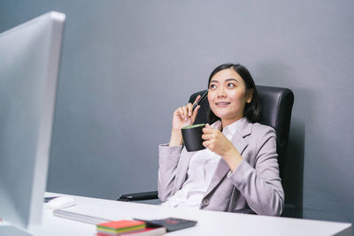 Young woman using phone while sitting on table