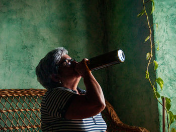 Woman drinking wine on chair at home