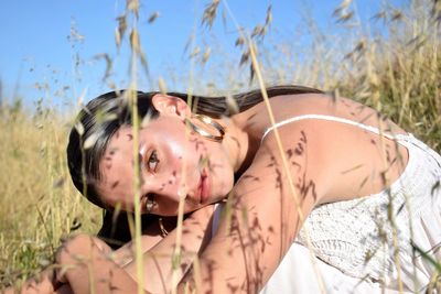 Portrait of young woman on sand in field