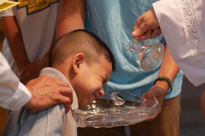 Midsection pastor giving baptism to boy in church 