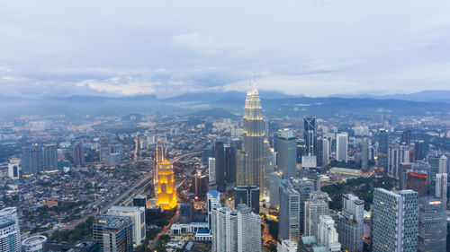 Aerial view of city lit up against sky