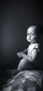 Portrait of baby boy sitting on bed