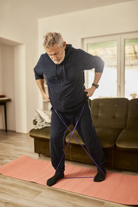 Active senior man exercising with resistance band at home