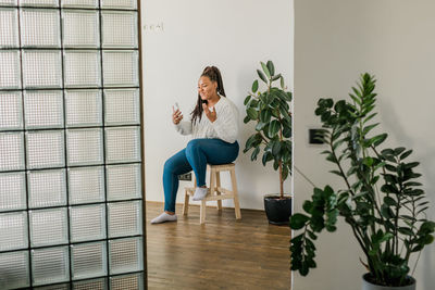 Portrait of young woman standing against wall