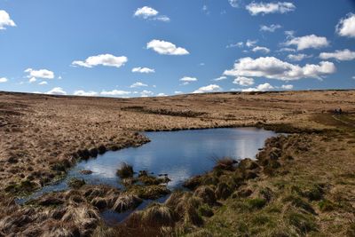 Scenic view of lake in moorland against blue sky