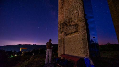 Rear view of man standing on field at night