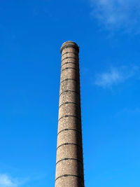 Low angle view of smoke stack against blue sky