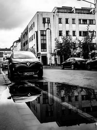 Cars on street in city against sky