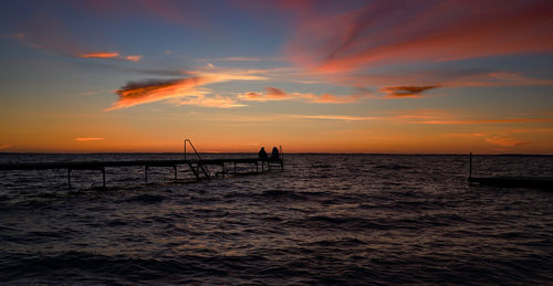 Silhouette people on beach against sky during sunset