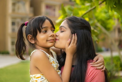 Aunt kissing niece in park