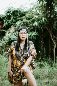 Portrait of young woman sitting on tree