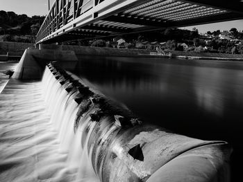 Footbridge over river against cloudy sky