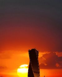 Low angle view of silhouette building against orange sky