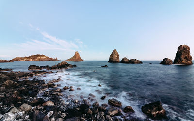 Scenic view of sea and rocks against clear sky