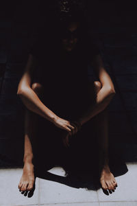 Midsection of woman sitting against black background