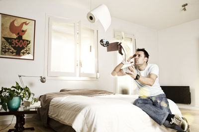 Full length of man levitating book and toilet paper using telekinesis at home