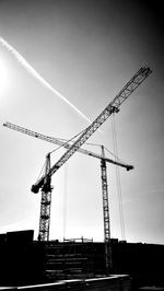 Low angle view of cranes at construction site against sky