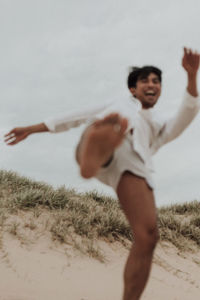 Full length of happy boy playing on sand at beach