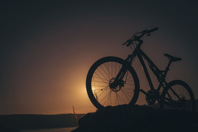 Silhouette bicycle against clear sky during sunset