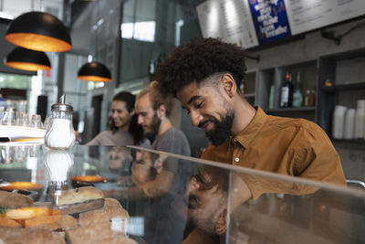 Smiling barista standing behind display cabinet in cafe