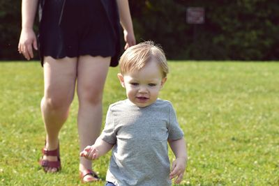 Low section of mother with baby boy on lawn