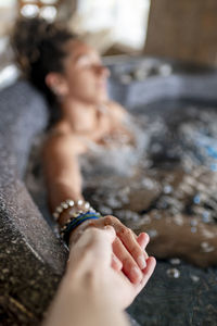 Mixed race woman holding someone hand while relaxing in a jacuzzi.