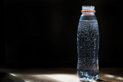 Close-up of glass bottle against black background