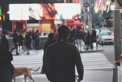 Rear view of people walking on street in city