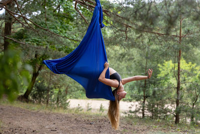 Full length of young woman jumping in forest