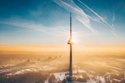 Communications tower in city during sunset