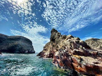 Rock formation in sea against sky