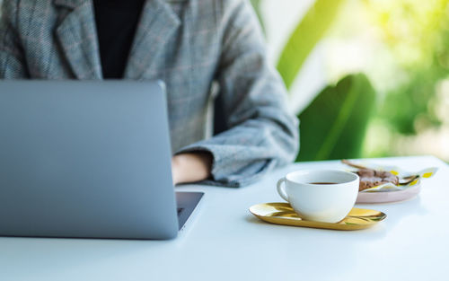 Midsection of woman using laptop at table