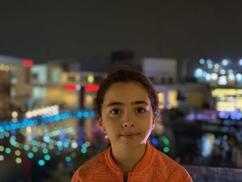 Portrait of young girl at night with colorful lights in background. 