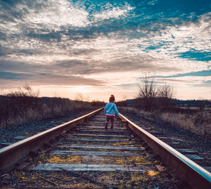  walking on railroad tracks during sunset