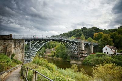 Arch bridge over river against sky