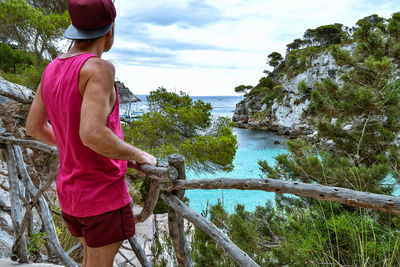 Man standing by railing against sea and sky